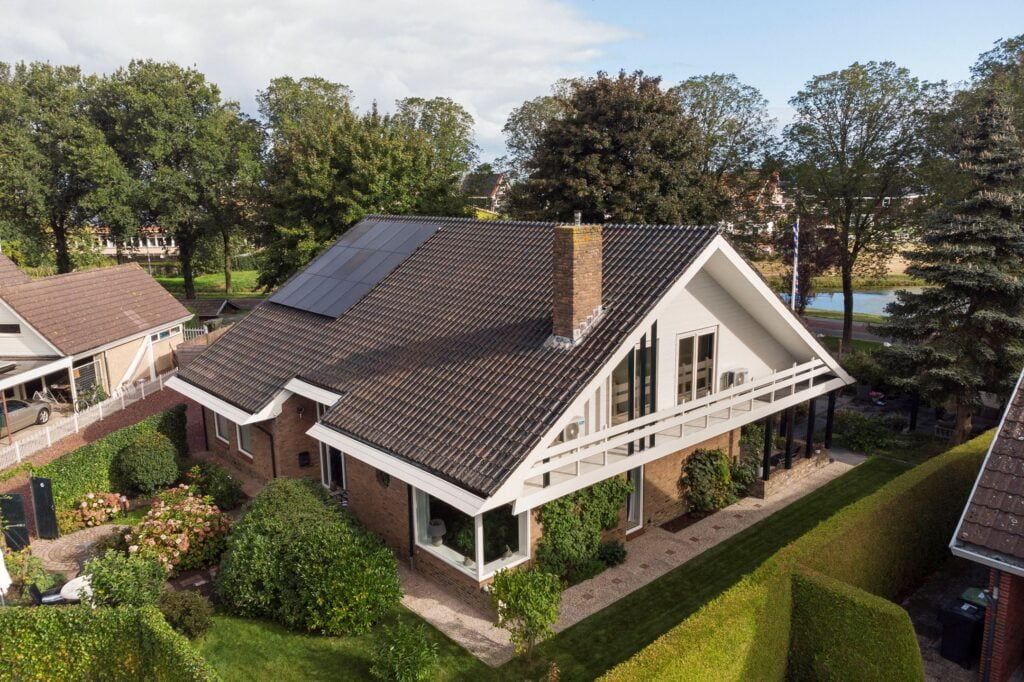 Luchtfoto van een vrijstaande woning met zonnepanelen aan het water in Friesland